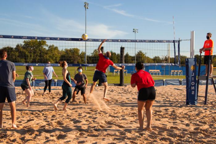 A group of individuals playing volley ball.